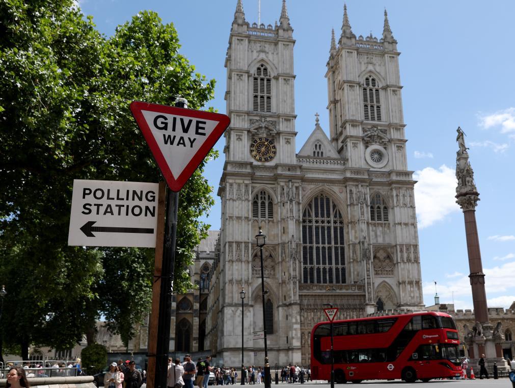 7月4日,在英国伦敦,一辆红色大巴经过威斯敏斯特教堂附近的一处投票站